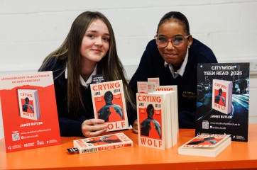 Two students with copies of the Teen Citywide Reading book, 'Crying Wolf' by James Butler