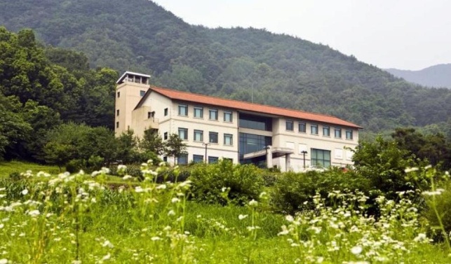 Toji Cultural Centre in Wonju. the centre is cream and terracotta building  surrounded by mountains and greenery
