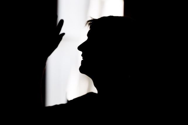 A silhouette of Emmet Kirwan performing a spoken word piece.